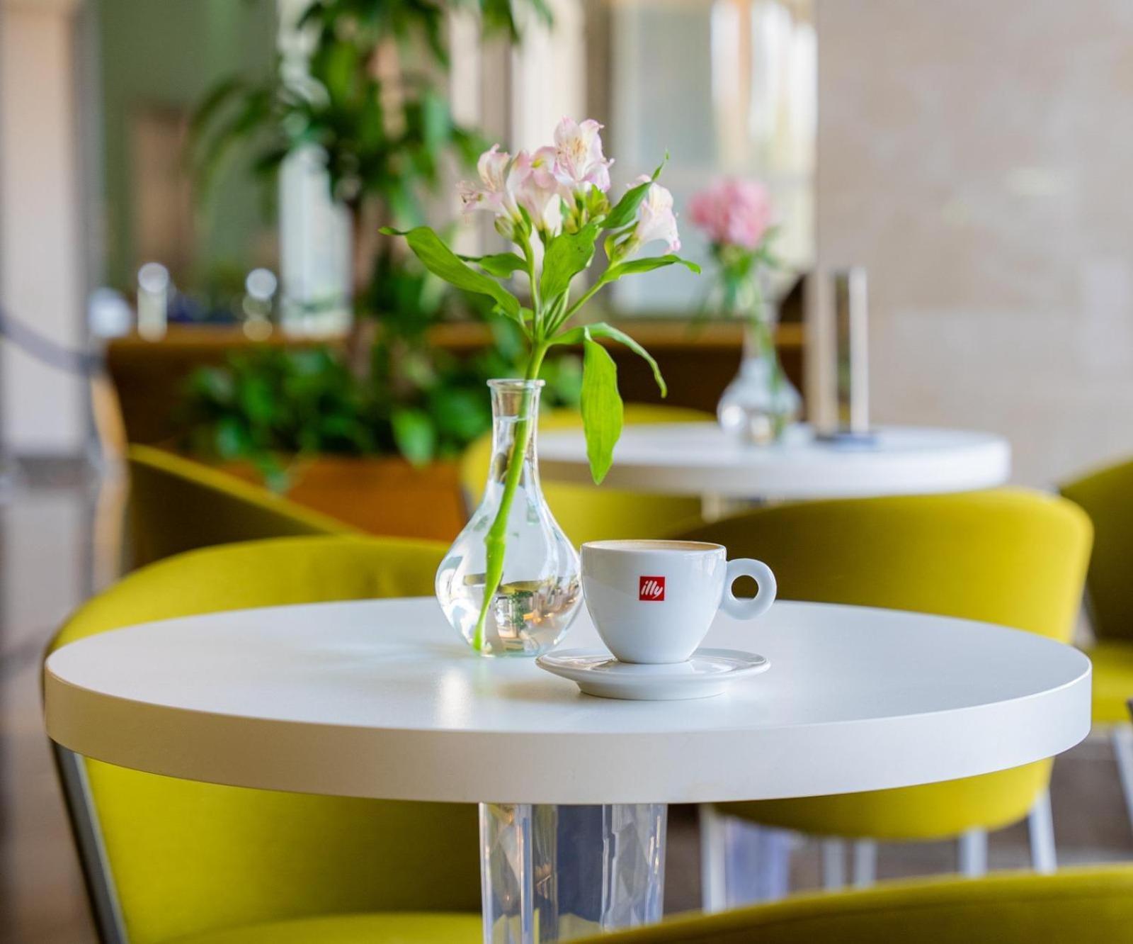 Marina Hotel Kuwait City Exterior foto A table with a flower vase and a cup of coffee